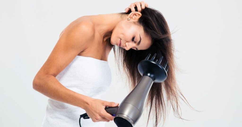 Chica secandose el pelo con un secador y difusor